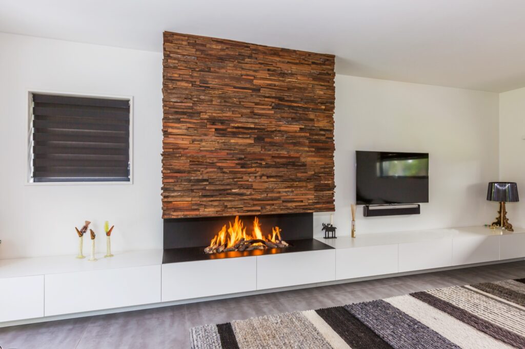 Moderne witte houthaard met bruine stenen en kastmeubel.