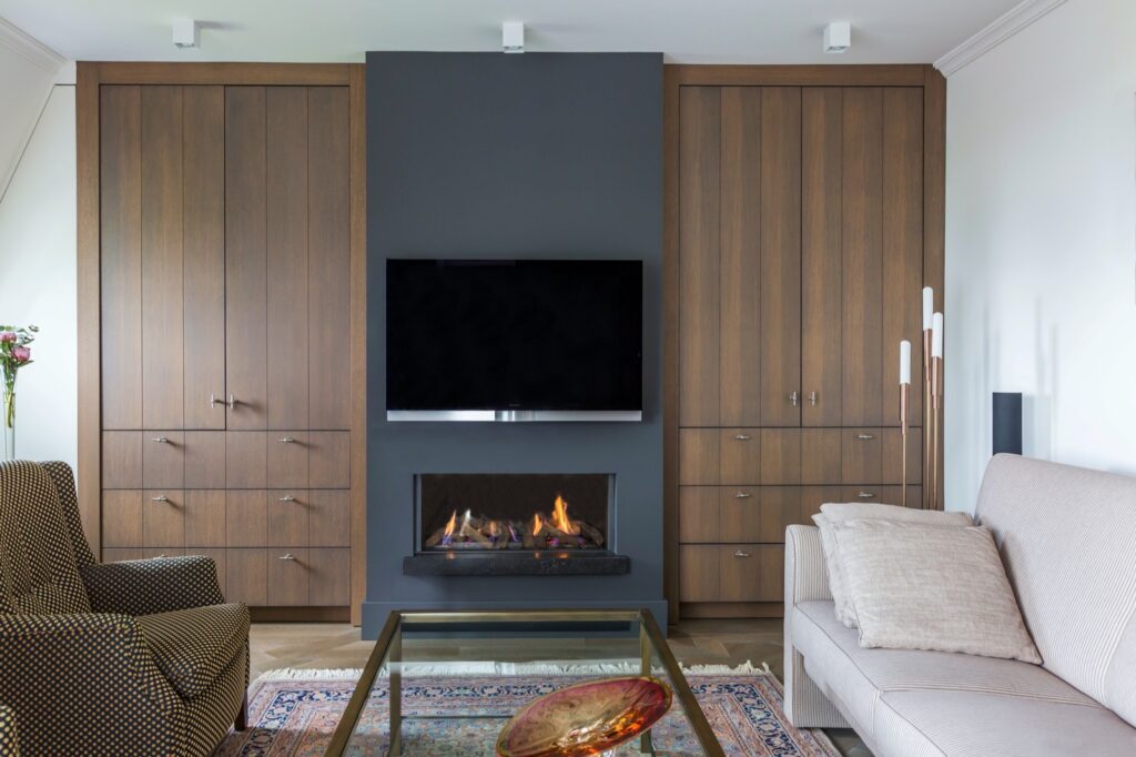 Zwarte elektrische haard ingebouwd in kastenwand met tv erboven